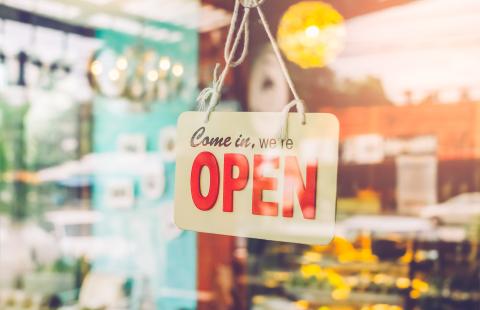 A red lettered open sign hanging in a shop window