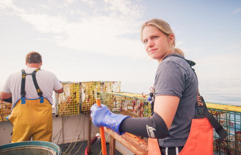 A woman on a fishing boat with a man in the distance with his back to the camera