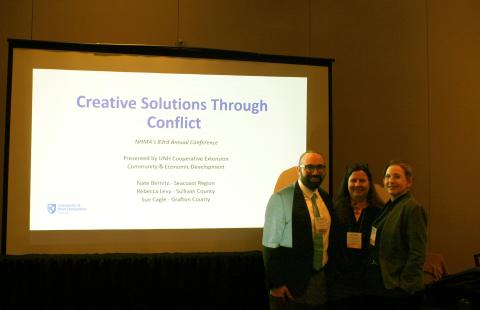 Nate Bernitz, Sue Cagle and Becky Levy standing in front of a presentatin screen at the NH Municipal Association conference