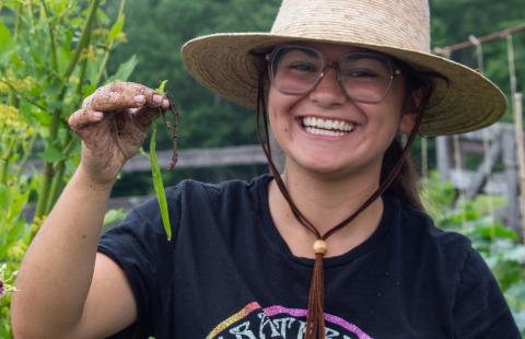 college student smiling in a garden with a bean