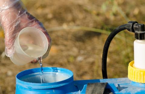 Person pouring chemicals into a sprayer