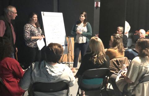 a group of people in conversation around a flip chart