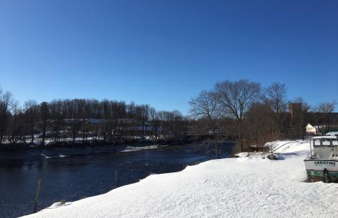 Photo taken from the side of a river with snow on the ground