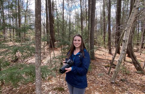 Amy Arsenault poses in the woods with her camera