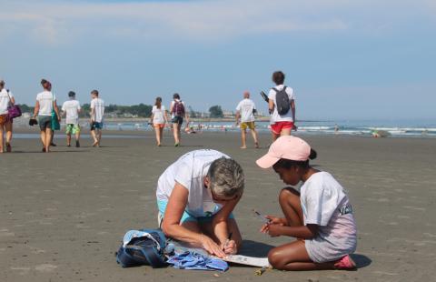 A citizen scientist volunteer works with a youth at the Beach Blitz event.