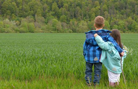 Children embracing in a field