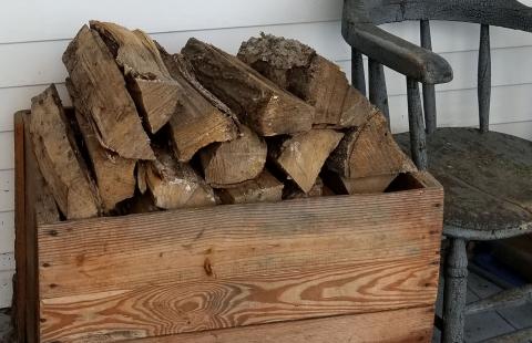 wood pile in wood box beside wooden chair