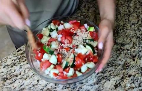 Mixing bowl of rice salad with tomatoes and cucumbers.