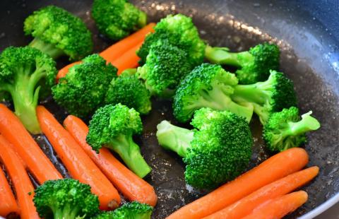Skillet with broccoli and carrots being stir fried.