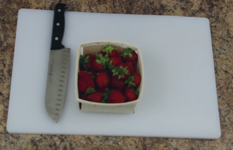 Basket of fresh picked strawberries with knife and cutting board.