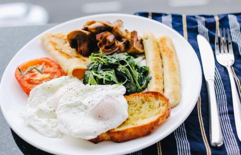 Plate with breakfast food including eggs, spinich, tomatoes, sausage, toast