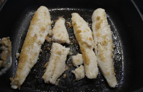 Seasoned catfish cooking in skillet.