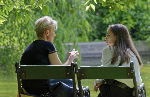 Mother talking with daughter while sitting on park bench