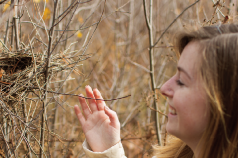 woman outdoors looking at a bird's nest