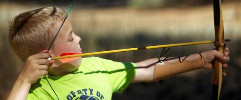 young boy shooting shooting with a bow