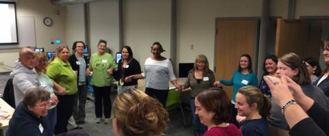 People at a workshop stand in a circle holding hands