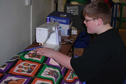 A boy sewing a quilt.