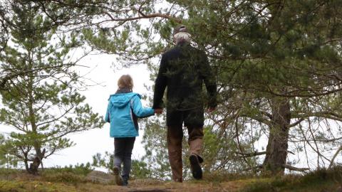 Grandfather walking in woods with granddaughter