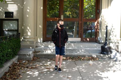 Boy wearing mask in front of school