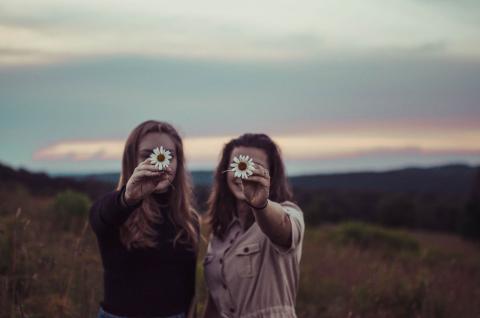 Young women holding up daisies