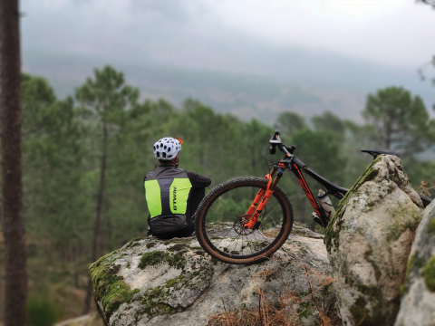 Biker sitting on mountain next to bike