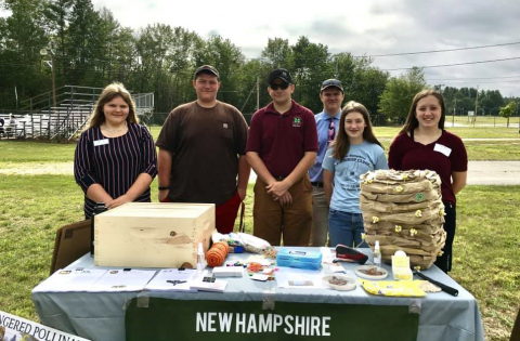 six teens in front of a table in a field