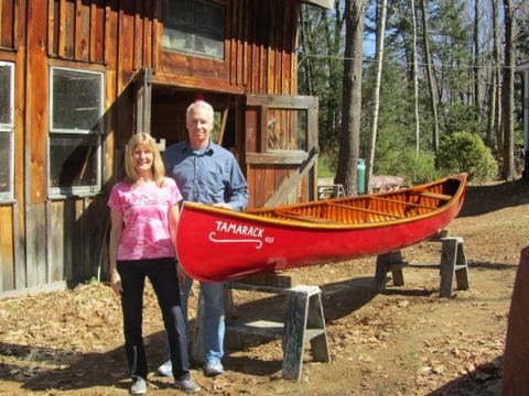 Karen standing with restored Tamarack canoe