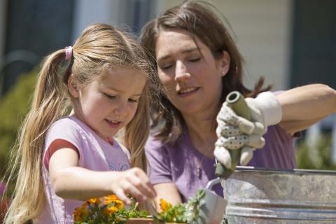 A girl and a female grown-up are gardening together.