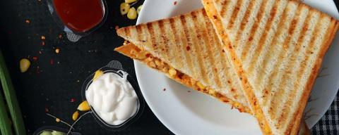 Grilled Cheese sandwich on a plate with condiments nearby and a napkin
