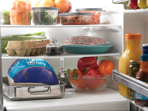 A picture of a refrigerator with a turkey thawing inside.