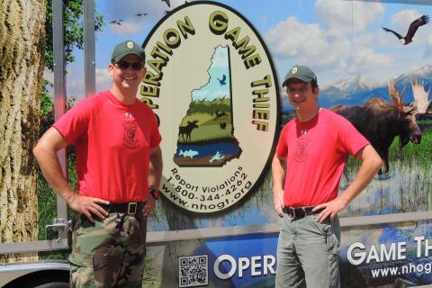 Two Fish and Game officers standing in front of a trailer.