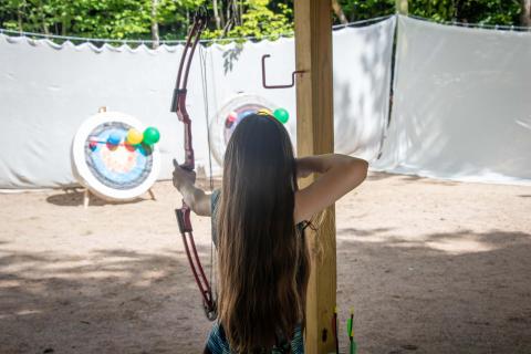 A female archer aiming for a target.