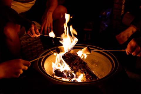 Picture of a campfire and a group of people are roasting marshmallows.