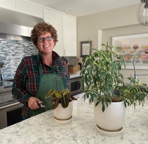Patti in her kitchen next to her potted plants