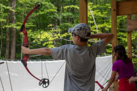 Boy aims bow and arrow