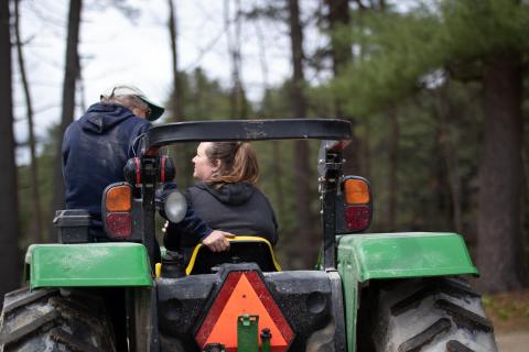 Two women sitting on a green tractor talking with each other