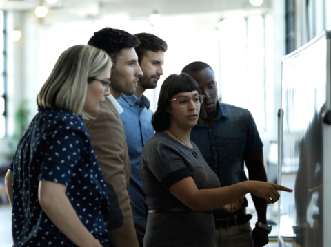 group of people looking at a white board