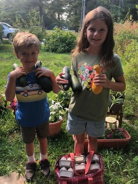 Picture are two children with fresh garden produce donations.