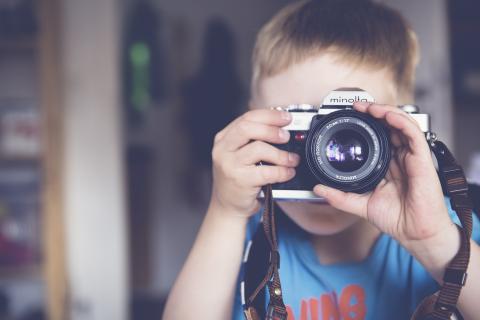 A boy looking througha camera lens.