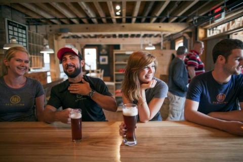 Patrons sitting at a bar with glasses of beer