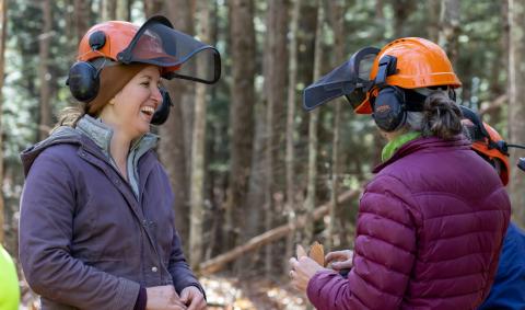 women laughing in the woods wearing hard hats
