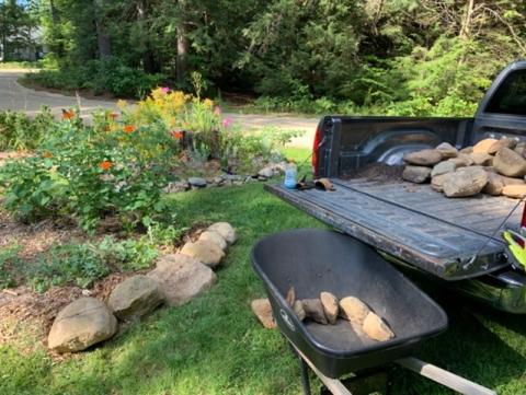 Rocks in wheelbarrow and truck, also lining garden bed