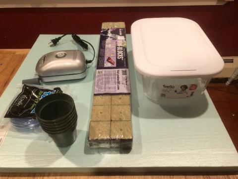 Pictured are supplies to build a home hydroponics raft system: plastic box, compressor, small pots, floatation material.