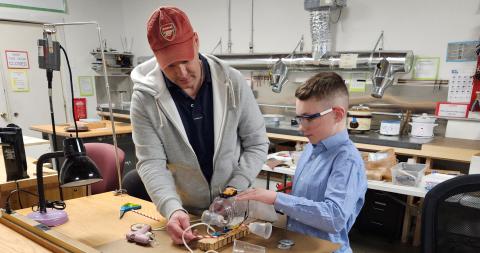 youth and mentor in classroom working on a project at a table