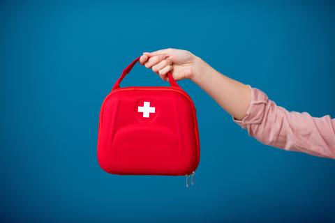 A hand holding a first aid kit