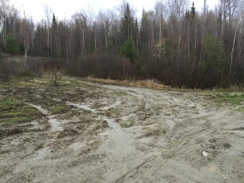 Wet muddy trail in the field with vehicle tracks