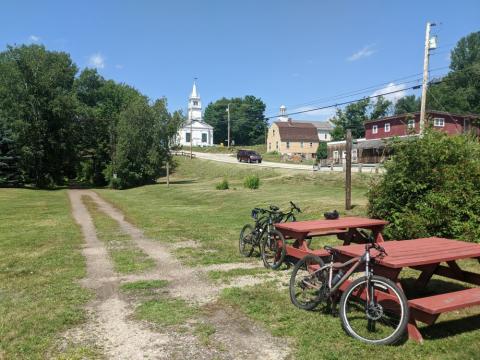 Picnic tables and dirt bikes alongside airt trail in a rural town