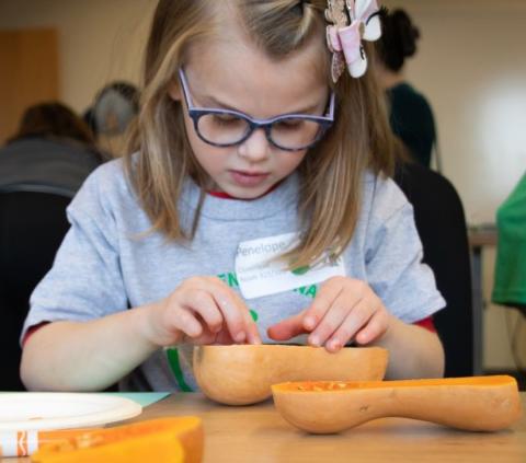 Young girl counting seeds of a butternut squash