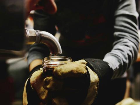 person filling jar with maple syrup