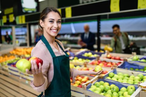 Woman standing in the grocery store holding an apple